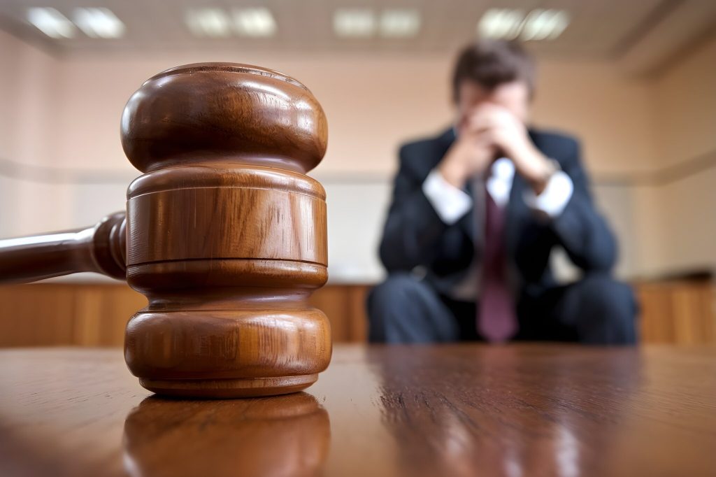 Legal issues. Man holds hands over face in court